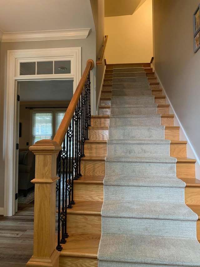 stairway with hardwood / wood-style floors and ornamental molding