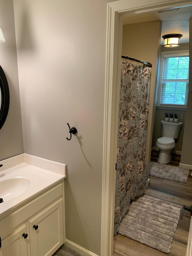 bathroom featuring vanity, toilet, wood-type flooring, and walk in shower