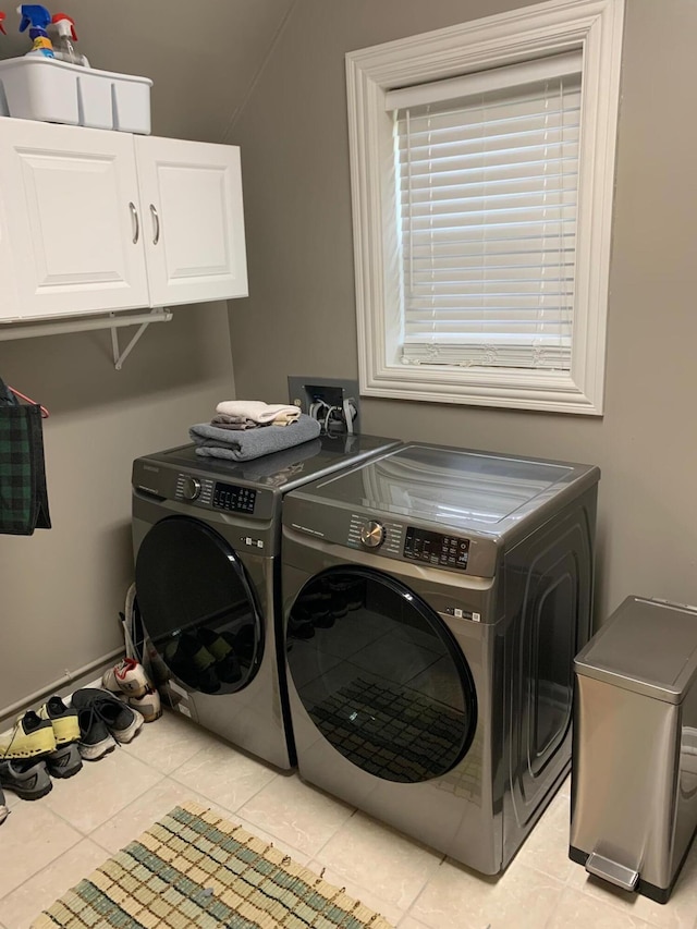 washroom featuring washer and clothes dryer, light tile patterned floors, and cabinets