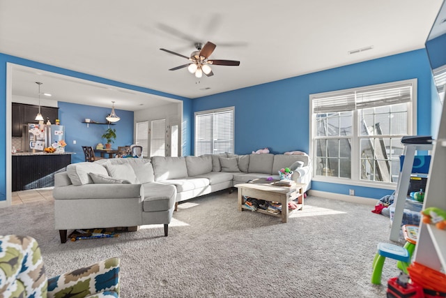 living room featuring plenty of natural light, light carpet, and ceiling fan