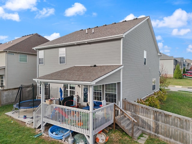 back of property featuring a yard, a trampoline, and a wooden deck