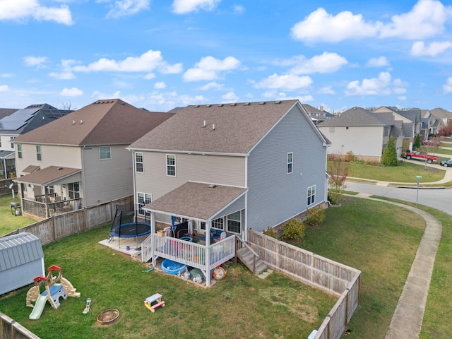 back of property featuring a yard, a trampoline, and a deck