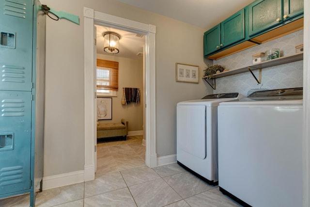 washroom featuring washing machine and clothes dryer, light tile patterned floors, and cabinets