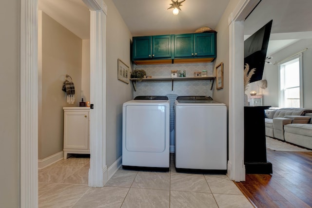 clothes washing area featuring cabinets, light tile patterned floors, and washer and dryer