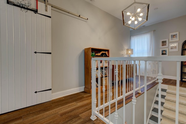 stairway with wood-type flooring and an inviting chandelier