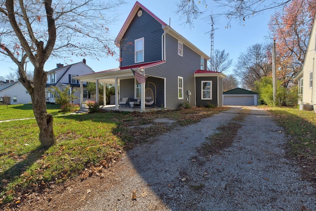 view of front of home with a garage, covered porch, an outbuilding, and a front yard