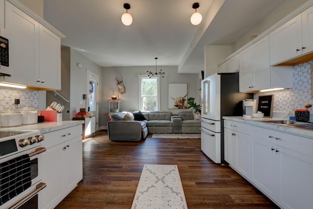 kitchen with decorative backsplash, dark hardwood / wood-style floors, white cabinetry, and a chandelier