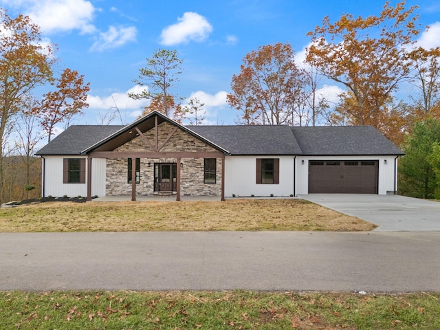 view of front of home featuring a front lawn, covered porch, and a garage