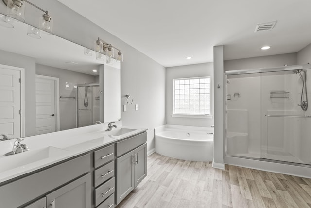 bathroom with vanity, hardwood / wood-style floors, and plus walk in shower