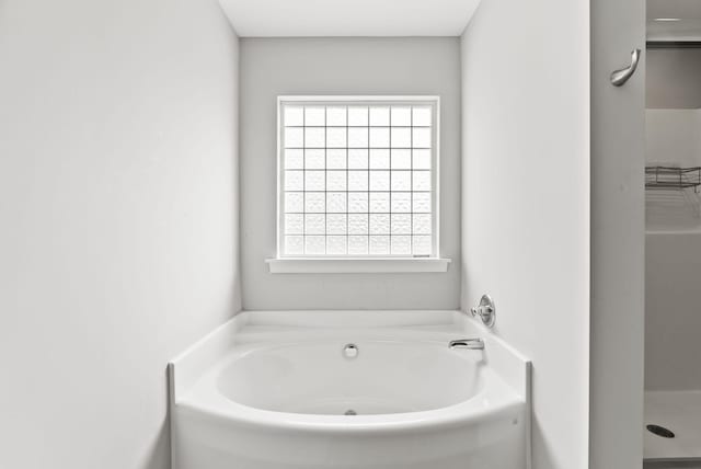 bathroom with a wealth of natural light and a bath