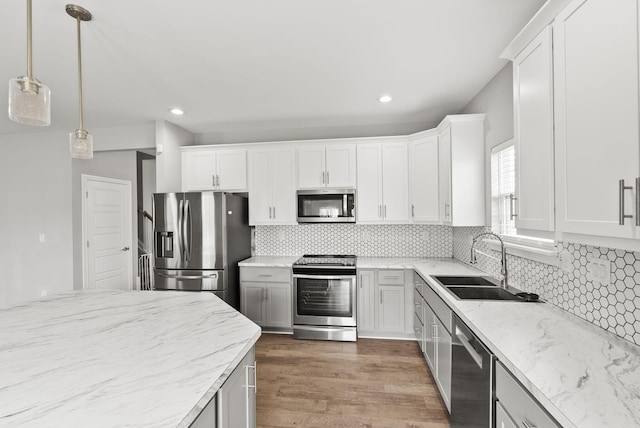 kitchen with dark hardwood / wood-style flooring, stainless steel appliances, sink, white cabinets, and hanging light fixtures