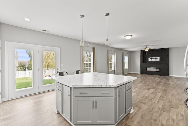 kitchen with a center island, decorative light fixtures, gray cabinets, and a wealth of natural light