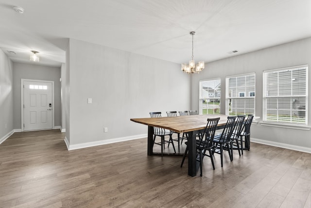 dining area with dark hardwood / wood-style floors and a notable chandelier