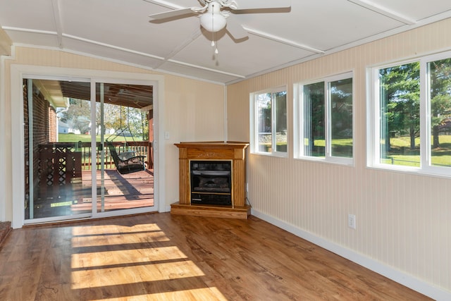 unfurnished living room with wooden walls, ceiling fan, wood-type flooring, and lofted ceiling