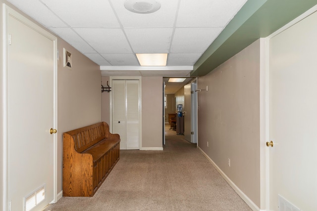 hallway featuring light carpet and a paneled ceiling