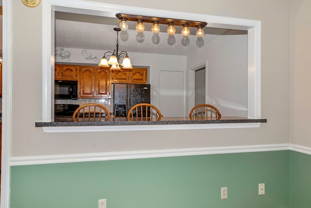 kitchen with black appliances, decorative light fixtures, and an inviting chandelier