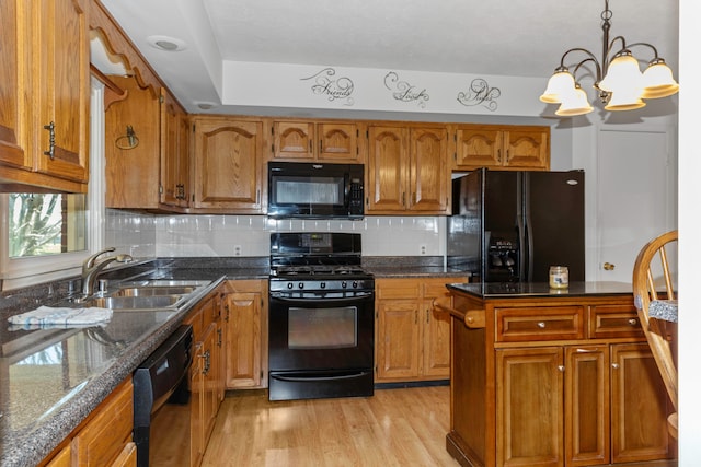 kitchen featuring a notable chandelier, black appliances, sink, decorative light fixtures, and light hardwood / wood-style floors