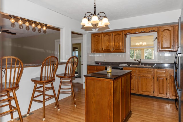 kitchen featuring a kitchen island, light wood-type flooring, sink, and tasteful backsplash