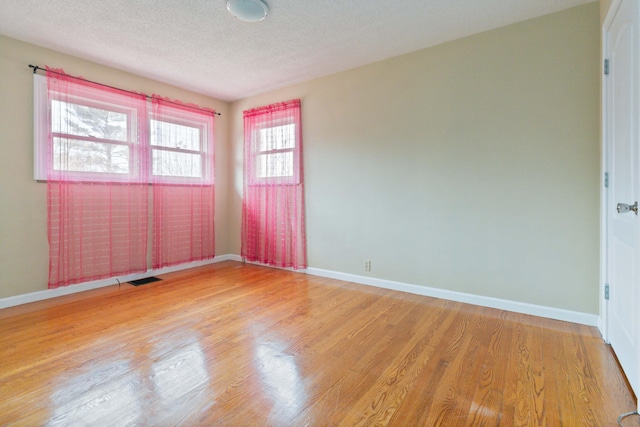 unfurnished room with plenty of natural light, light hardwood / wood-style floors, and a textured ceiling