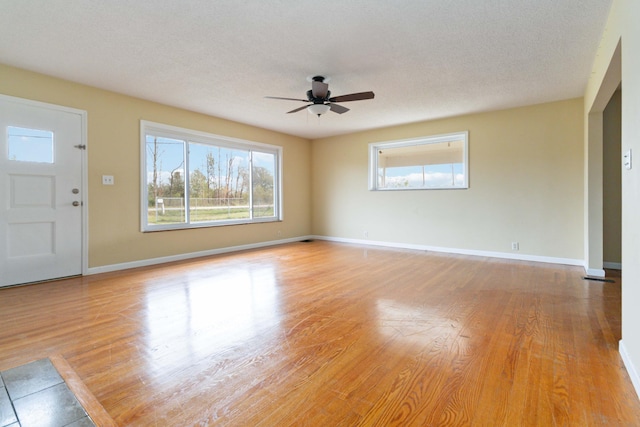 unfurnished living room featuring ceiling fan, light hardwood / wood-style flooring, and a textured ceiling