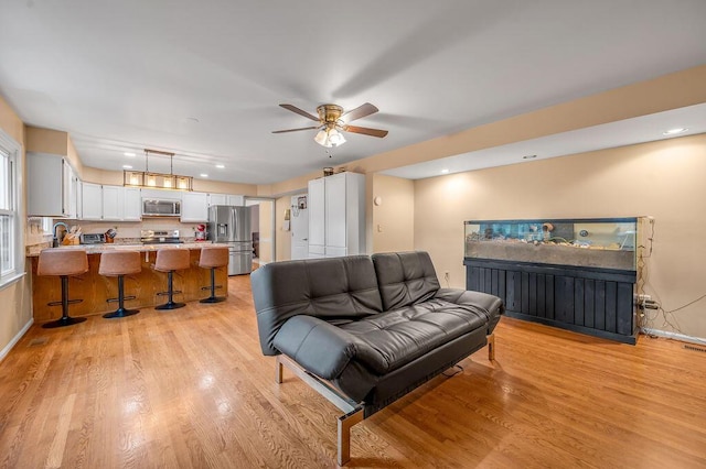 living room with light hardwood / wood-style flooring and ceiling fan