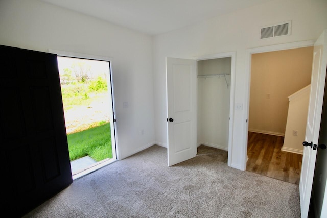 unfurnished bedroom featuring access to exterior, light carpet, and a closet