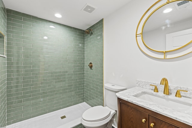 bathroom featuring tiled shower, vanity, and toilet