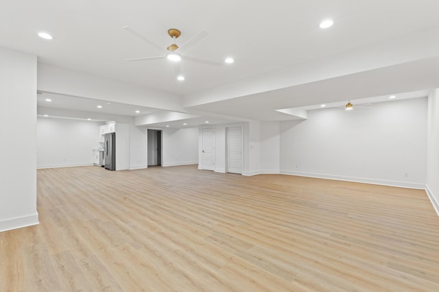 basement with ceiling fan, stainless steel fridge, and light wood-type flooring