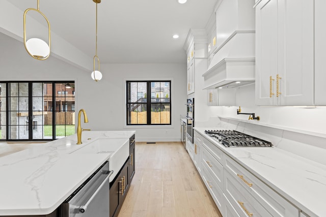 kitchen featuring white cabinets, pendant lighting, light stone counters, and light hardwood / wood-style floors