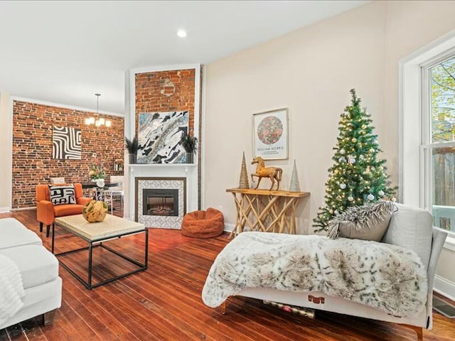 living room featuring hardwood / wood-style flooring, brick wall, and a chandelier