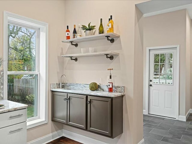 bar with a healthy amount of sunlight, dark hardwood / wood-style flooring, and sink