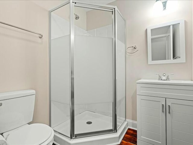 bathroom with wood-type flooring, vanity, toilet, and a shower with door