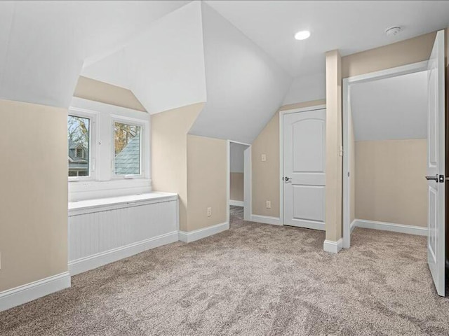 bonus room with light carpet and vaulted ceiling