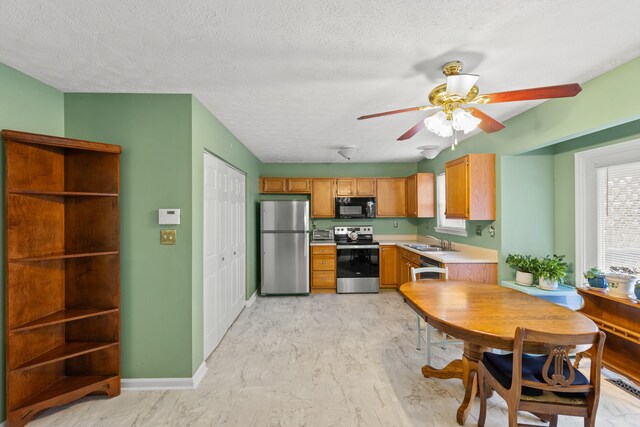 kitchen with a textured ceiling, sink, stainless steel appliances, and light hardwood / wood-style flooring