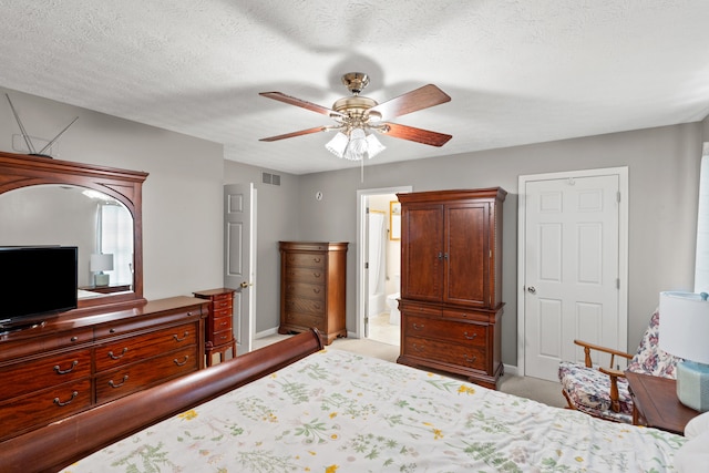 bedroom featuring ceiling fan, light colored carpet, a textured ceiling, and ensuite bath