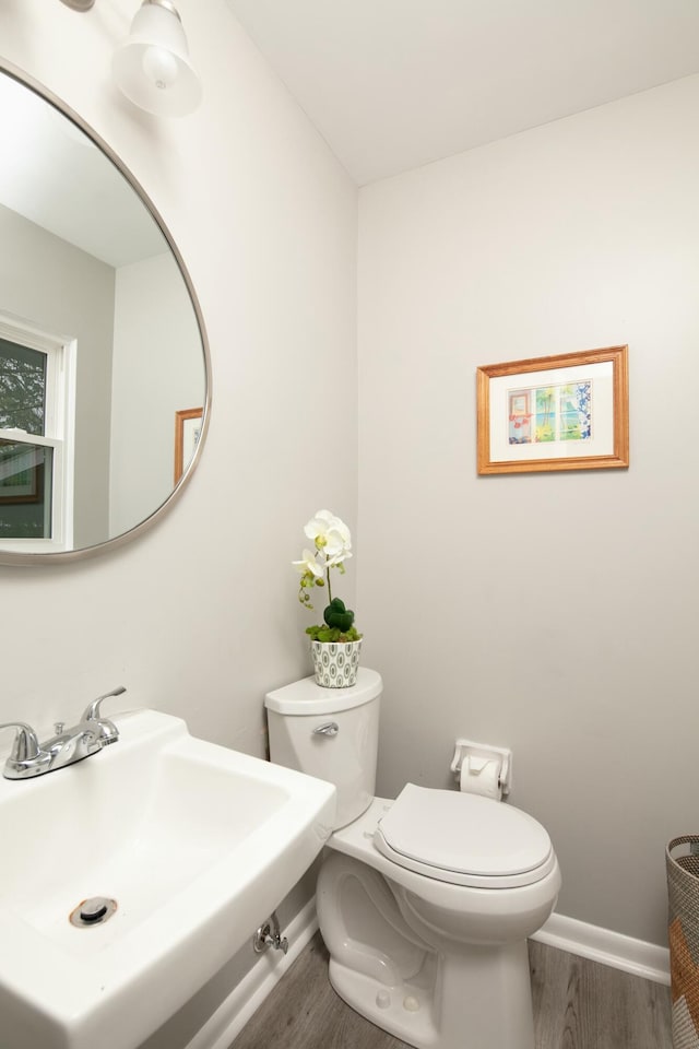 bathroom with toilet, baseboards, a sink, and wood finished floors