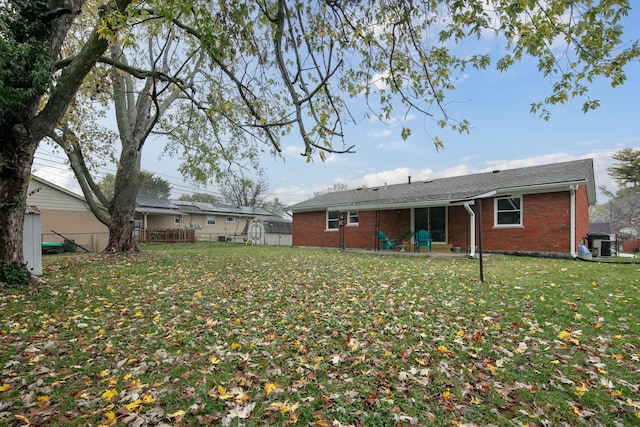 back of property with a lawn, a patio, fence, central air condition unit, and brick siding