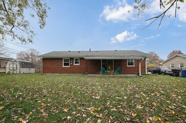 back of property with an outbuilding, brick siding, a yard, a storage unit, and a patio area