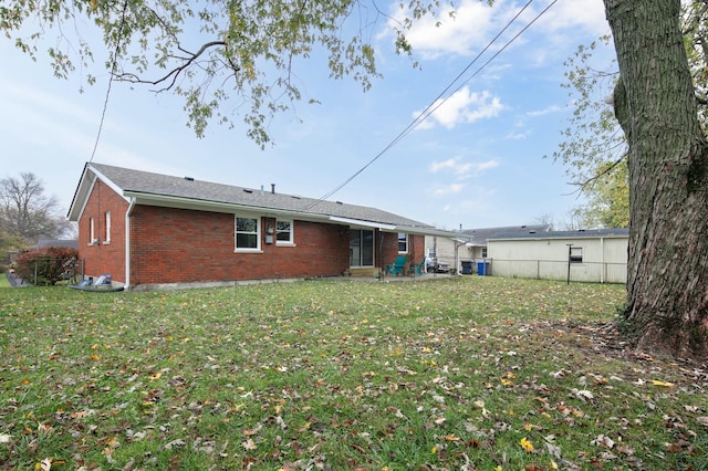 rear view of property featuring a yard, brick siding, a patio area, and fence