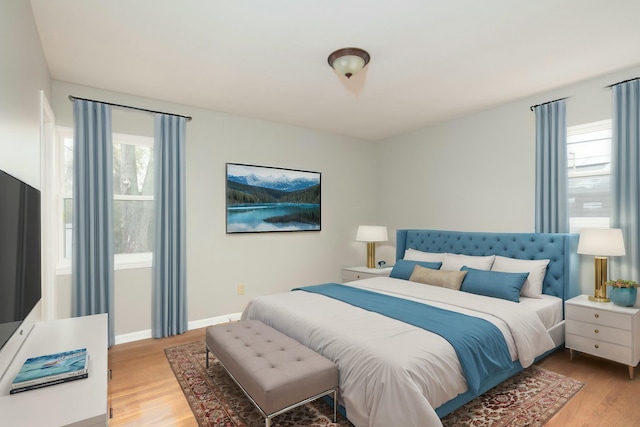 bedroom with light wood finished floors, multiple windows, and baseboards