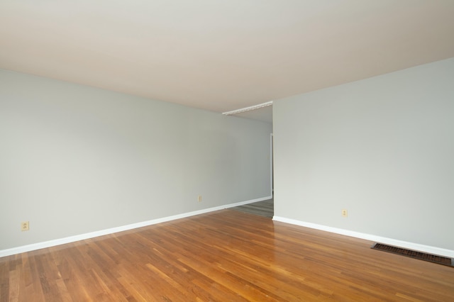 unfurnished room featuring wood finished floors, visible vents, and baseboards