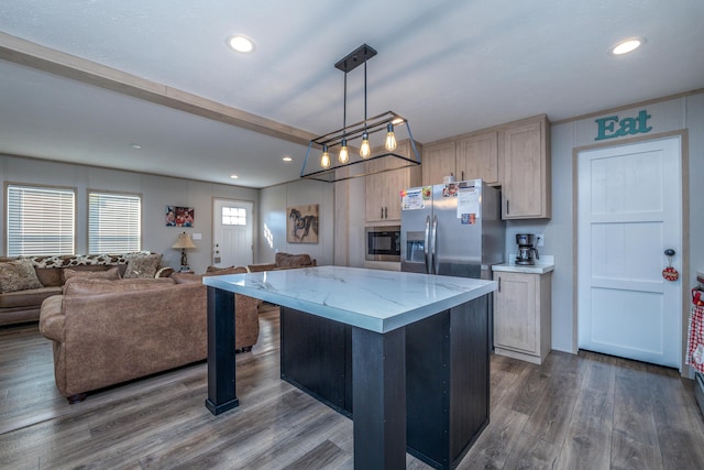 kitchen with a center island, light brown cabinets, black microwave, hanging light fixtures, and dark hardwood / wood-style floors