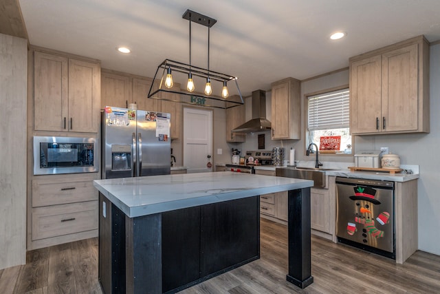 kitchen with pendant lighting, appliances with stainless steel finishes, a kitchen island, wall chimney range hood, and sink