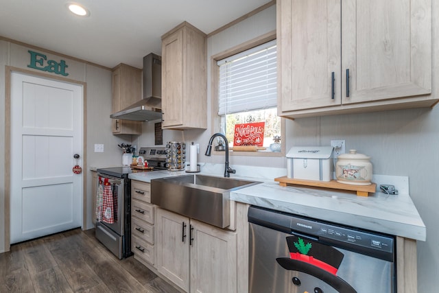 kitchen featuring appliances with stainless steel finishes, wall chimney range hood, light brown cabinets, dark hardwood / wood-style flooring, and sink