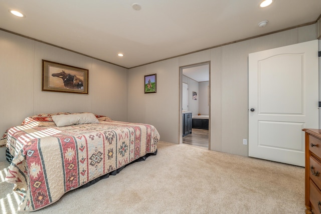 bedroom featuring ensuite bathroom, light colored carpet, and ornamental molding