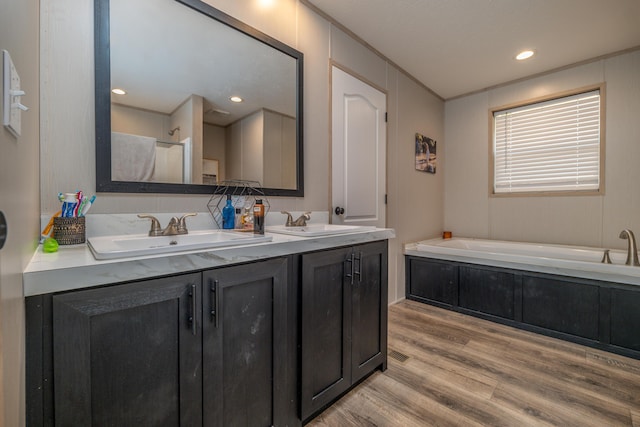 bathroom with vanity, a relaxing tiled tub, and hardwood / wood-style floors