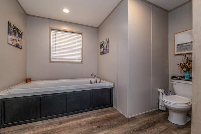 bathroom with hardwood / wood-style floors, tiled tub, ornamental molding, and toilet