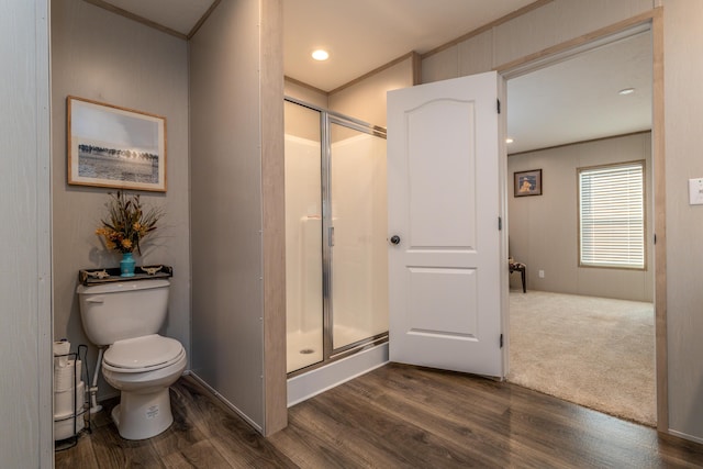 bathroom featuring a shower with shower door, hardwood / wood-style floors, toilet, and ornamental molding