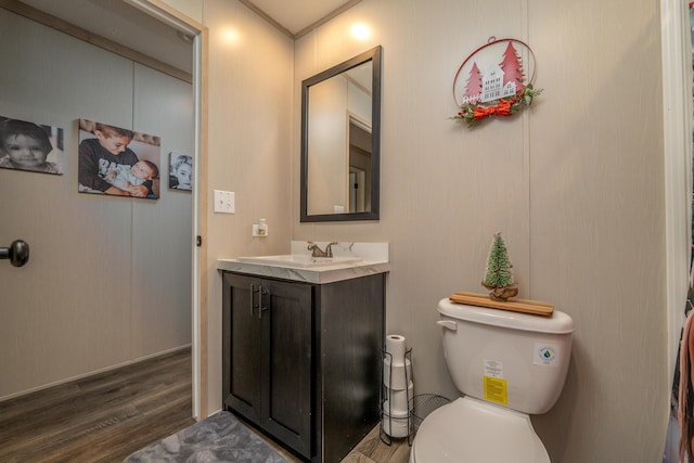 bathroom with toilet, vanity, crown molding, and hardwood / wood-style floors