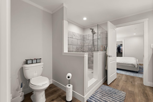 bathroom featuring crown molding, toilet, wood-type flooring, and tiled shower